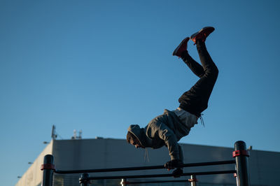 Low angle view of man jumping on steps against clear sky