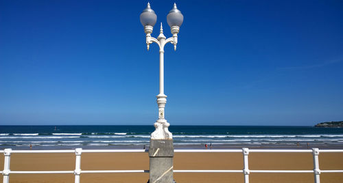 Street light on beach against clear blue sky