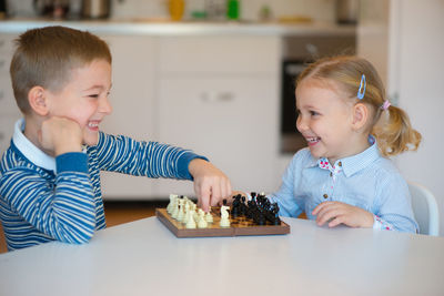 Cute sibling playing chess at home