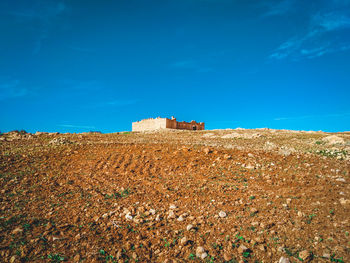 Buildings on field against blue sky