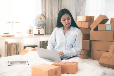 Young woman using mobile phone while sitting on bed