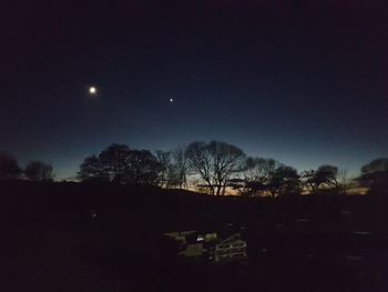 Silhouette trees against sky at night