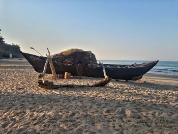 Boat moored on beach against clear sky