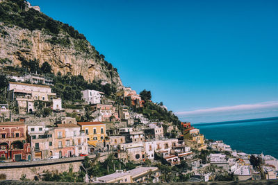 Townscape by sea against blue sky