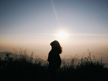 Silhouette woman standing on land against sky during sunset