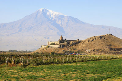 Scenic view of built structure against snowcapped mountain and sky