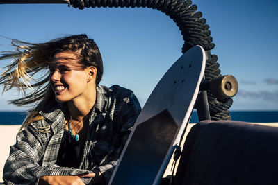 Woman with skateboard in vehicle at beach