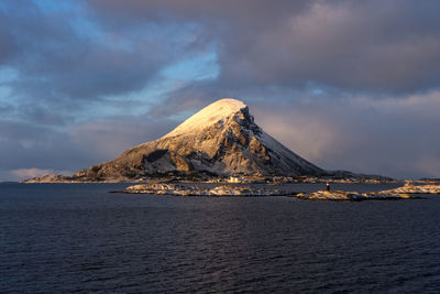 Scenic view of sea by snowcapped mountain against sky