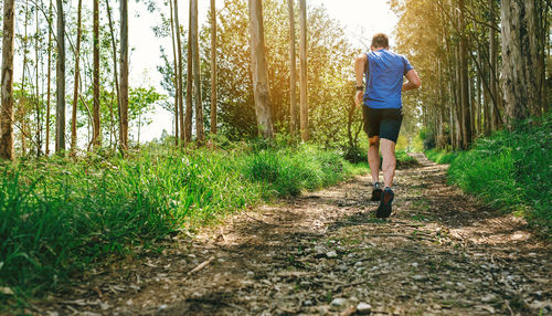 Rear view of man running on footpath