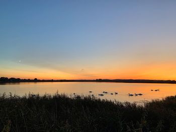 Scenic view of lake against romantic sky at sunset