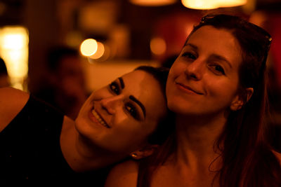 Portrait of smiling woman with friend in city at night