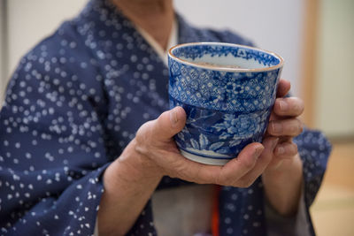 Midsection of person holding japanese tea cup