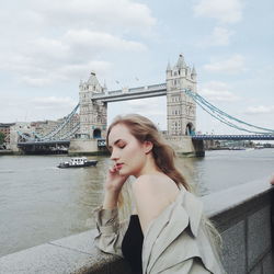 Woman standing against tower bridge over thames river in city