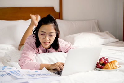 Young woman using laptop on bed at home