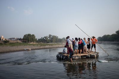 People fishing in river against sky