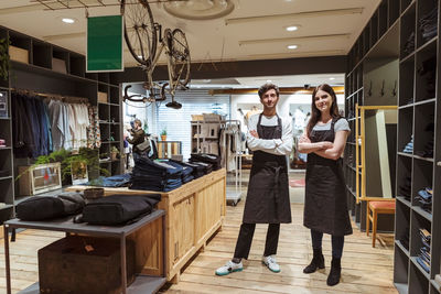 Portrait of confident colleagues standing with arms crossed in boutique