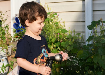 Little boy playing with a watering hose in the backyard