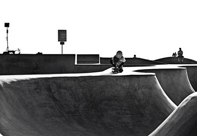 Teenager with skateboard on ramp against clear sky