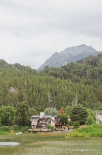 Houses by trees on mountain against sky