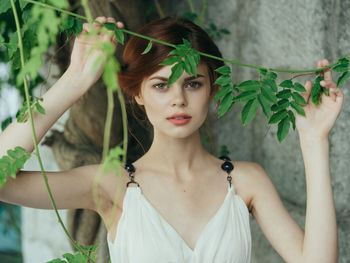 Portrait of young woman standing while holding plant
