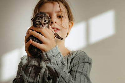 Happy girl holding a newborn kitten in her arms.