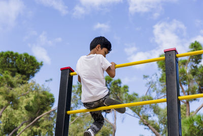 Young boy enjoying playing at the playground in the park.