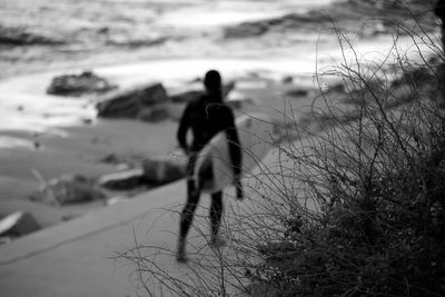 Rear view of surfer walking at beach