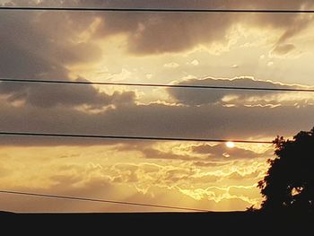 Low angle view of power lines against sky during sunset