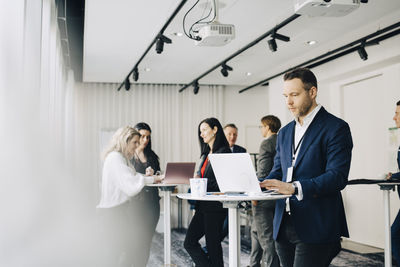 Businessman working over laptop while standing in office seminar