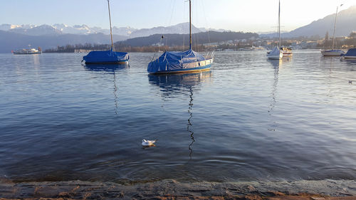 Sailboats moored on sea against sky