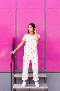 Young woman standing against wall