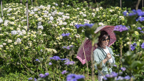 Woman with umbrella standing in the garden