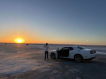 Cars on road against clear sky during sunset
