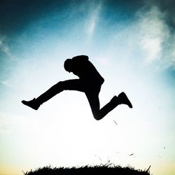 Low angle view of silhouette woman jumping against sky