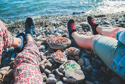 Low section of friends sitting on rocky beach