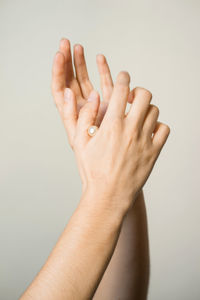 Cropped hands holding pearl against beige background