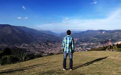 Rear view of man standing on landscape against sky