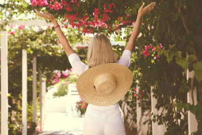 Rear view of woman standing by flowering tree