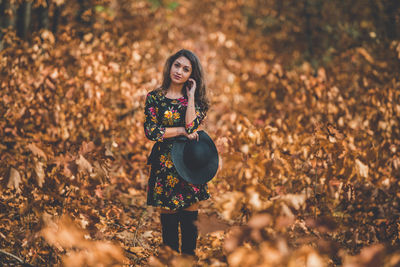 Portrait of woman standing on leaves during autumn