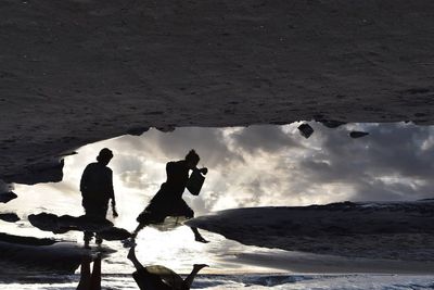 Silhouette people standing on snow covered mountain against sky