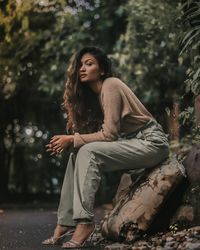 Beautiful young woman with umbrella against trees