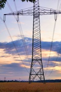 Low angle view of electricity pylon on field against sky