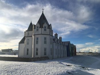 Church by building against sky in winter