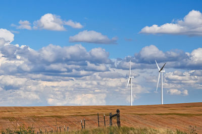 Windmills on field against sky