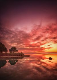 Scenic view of lake against dramatic sky during sunset