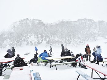 People on snow covered field against sky