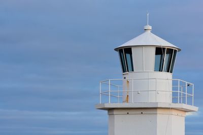 Lighthouse by building against sky