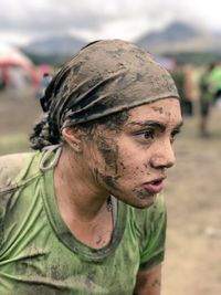 Close-up of thoughtful dirty young woman standing on field