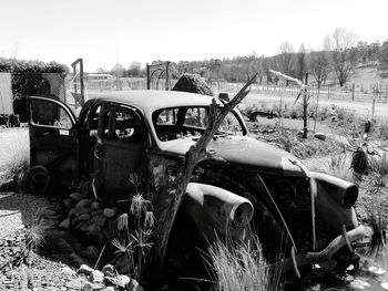 Abandoned car on field against sky