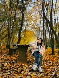 Full length of teenage girl standing by tree during autumn